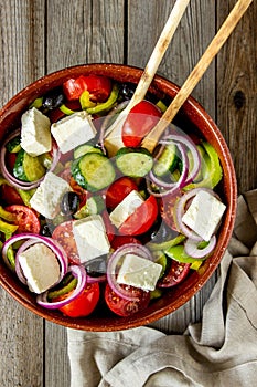 Greek salad on a wooden background. Tomatoes, peppers, olives, cheese, onions. Healthy eating. Diet. Vegetarian food