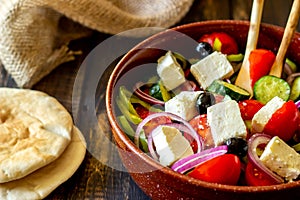 Greek salad on a wooden background. Tomatoes, peppers, olives, cheese, onions. Healthy eating. Diet. Vegetarian food