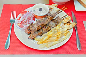 greek souvlaki with fries and cream cheese on a table in a restaurant