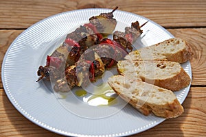 Greek style lamb meat souvlaki skewer from the grill served with slices of rustic bread.