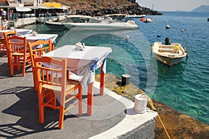 Greek tavern with orange wooden chairs by the sea coast, Greece,