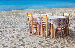 Greek taverna table and chairs on sandy beach