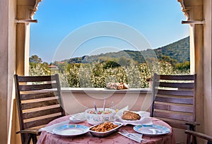 A Greek traditional lunch served on a wooden table at home with a view with olives trees, outdoors