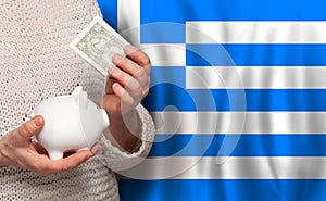 Greek woman with money bank on the background of Greece flag. Dotations, pension fund, poverty, wealth, retirement concept