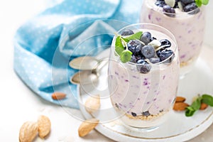 Greek yogurt or blueberry parfait with fresh berries and almond nuts on white background
