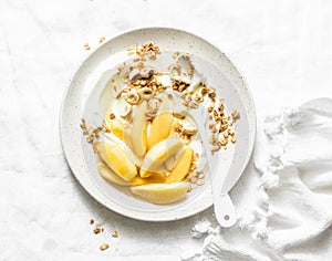 Greek yogurt with caramelized quince, granola, hazelnut on light background, top view. Delicious breakfast, dessert