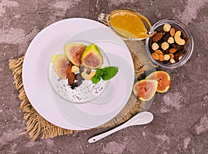 Greek yogurt with figs, nuts and honey in a bowl on a gray background. View from above.