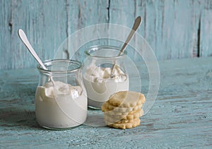 Greek yogurt in glass jars and shortbread on blue wooden surface