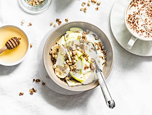 Greek yogurt with granola, banana, apple, honey on a light background, top view. Delicious breakfast