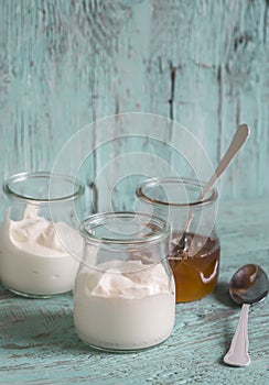 Greek yogurt and honey in a glass jar on blue wooden surface