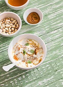 Greek yogurt with honey and nuts in a white bowl on wooden surface