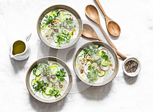 Greek yogurt soup with cucumber, radish, cilantro and nut on a light background, top view. Delicious vegetarian food. Flat lay