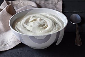 Greek yogurt in a white bowl on a rustic black wooden table