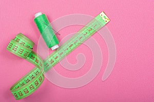 Green accessories for sewing on a pink background.