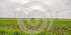 Green agricultural field with wind turbines under the cloudy sky