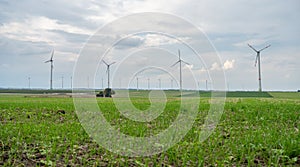 Green agricultural field with wind turbines under the cloudy sky