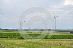 Green agricultural field with wind turbines under the cloudy sky