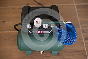 Green Air Compressor with Pressure Gauge on Wooden Floor