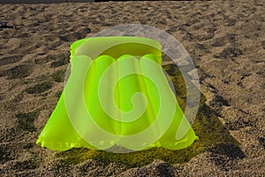 Green airbed lying on a sand