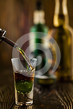 A green alcoholic drink is poured into a glass at a nightclub. at the bar. Preparation of a green cosmopolitan cocktail