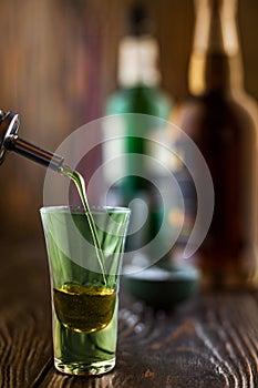 A green alcoholic drink is poured into a glass at a nightclub. at the bar. Preparation of a green cosmopolitan cocktail