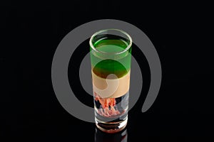 Green alcoholic shot glass with absent, irish cream, liquor on elegant dark black background