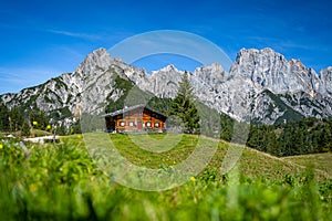 Green alpine meadow with wooden hut in front of impressive mountain peaks, Salzburg, Austria, Europe