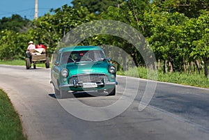 Green american classic car drive on the road in the countryside Santa Clara Cuba.