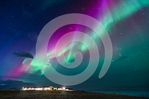 Green annd purple northern lights over a small village in Iceland