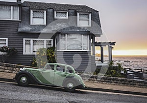 Green antique car parked on the road near a house in the beach