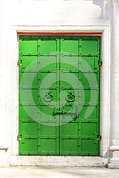 Green antique iron door with lock on white brick wall background