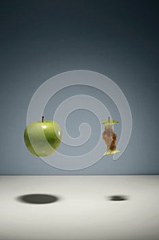 Green apple and apple core floating in the air. Conceptual image