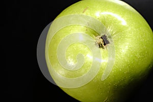 A green apple on a black background. Closeup.