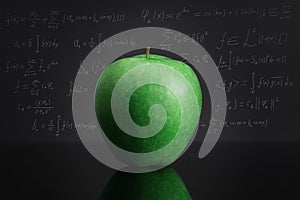 Green apple on black table against blackboard full of mathematical formulas