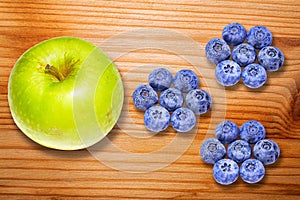 Green apple and blueberries on wooden desk