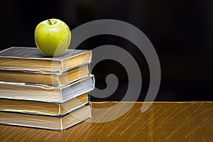 Green apple on the book. Blackboard with sign.