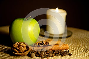 Green apple, cinnamon, walnut and a candle on the table