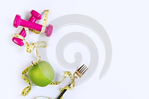 Green apple, dumbbell and tape measure on white table background. Selection of healthy food and exercise concept. Organic food,