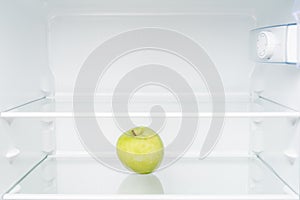 Green apple in empty refrigerator.