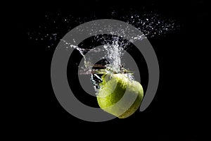 A green Apple falls into the water