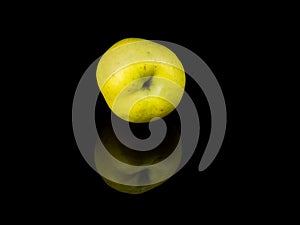 Green apple fruit on a black glass background with reflection