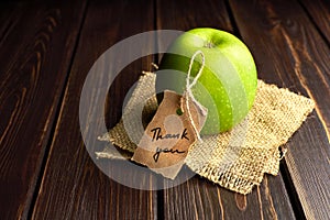 Green apple gift with thank you lable on dark wooden table background. Teachers day