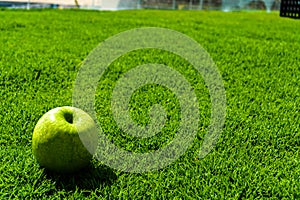 Green apple on green grass: simple and clear