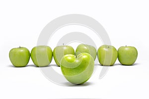 Green apple heart shaped in front of other green apples