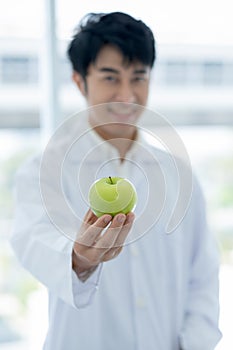 Green apple is held by smart scientist man in laboratory or classroom with concept of healthy fruit of good food for better health