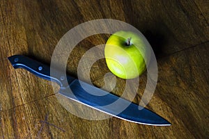 Green apple and knife on table