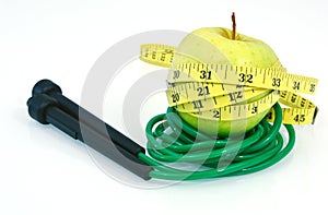 Green apple with measuring tape and jump rope on white background