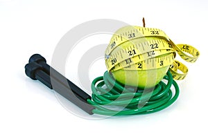 Green apple with measuring tape and jump rope on white background