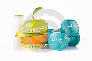 Green apple with measuring tape with a pair of blue fitness dumbbells and protein drink