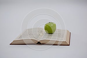 Green apple on open book